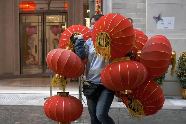 A worker wearing a face mask carries red lanterns, ahead of the Chinese Lunar New Year, following the coronavirus disease (COVID-19) outbreak, in Hong Kong, China on January 28, 2021. (Photo by Tyrone Siu/Reuters)