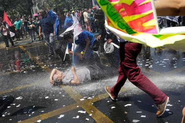 A demonstrator lies on the ground as they clash with riot policemen during a protest called by workers of the public sector to demand for an increase in their salaries in Santiago, Chile, November 10, 2016. (Photo by Pablo Sanhueza/Reuters)