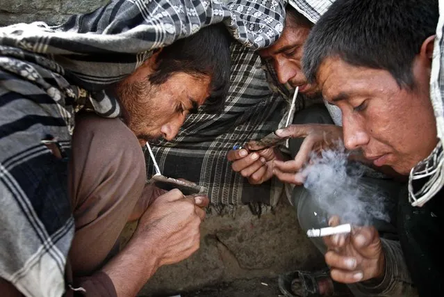 Drug addicts smoke heroin in Kabul, Afghanistan, on July 3, 2013. (Photo by Rahmat Gul/Associated Press)