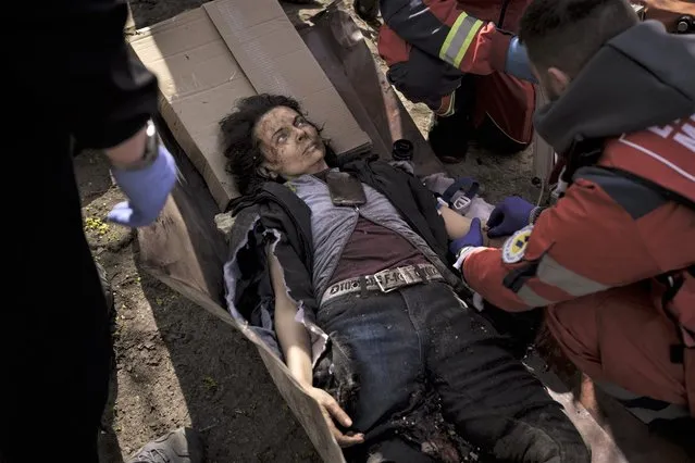 A woman injured in a Russian attack is treated by emergency workers in Kharkiv, Ukraine, Saturday, April 16, 2022. (Photo by Felipe Dana/AP Photo)