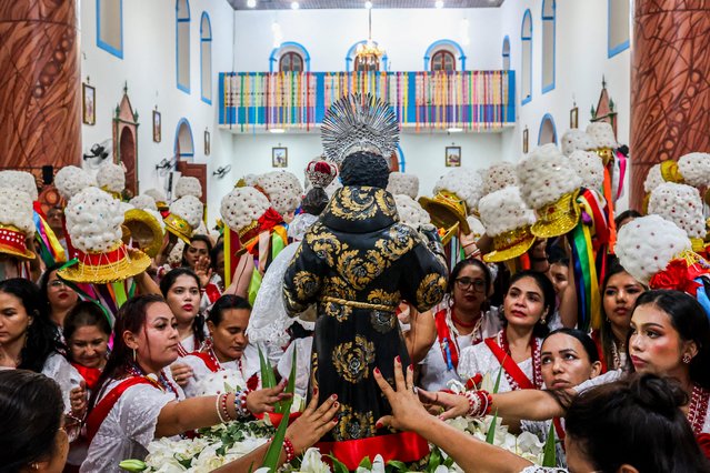Women touch the image of Saint Benedict as they participate in the Marujada in Braganca, Para State, Brazil, on December 26, 2024. A cultural heritage of Brazil, the Marujada is a traditional nine-day religious festival that pays homage to Saint Benedict (Sao Benedito), the “black saint”, and has one of its highlights on Christmas Day. (Photo by Anderson Coelho/AFP Photo)
