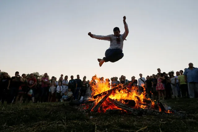 A man jumps over a campfire during a celebration on the traditional Ivana Kupala (Ivan the Bather) holiday in Kiev, Ukraine July 6, 2018. The ancient tradition, originating from pagan times, is marked with grand overnight festivities during which people sing and dance around campfires, believing it will purge them of their sins and make them healthier. (Photo by Valentyn Ogirenko/Reuters)