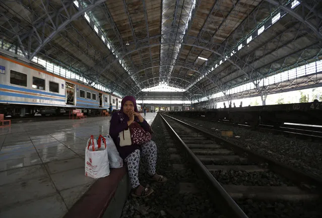 A passenger sits beside a railway as she waits for her train at the Tanjung Priok train station, two days after it was reopened, according to local media, in Jakarta, Indonesia December 23, 2015. (Photo by Reuters/Beawiharta)