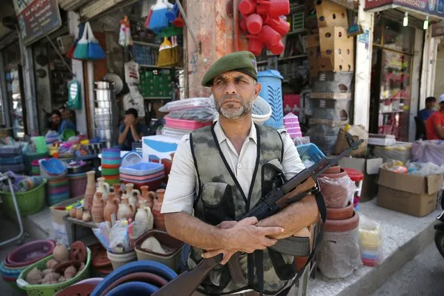 In this May 29, 2018 photo, a Syrian opposition fighter guards the market area in downtown al-Bab, Syria. Turkey is growing long-term roots in its northern Syrian enclave, nearly two years after its troops moved in, modeling the zone on its own towns and bringing in its own administrators and military, financial and security institutions. Turkey aims to keep out its nemesis, the U.S.-backed Syrian Kurdish militia known as the YPG. (Photo by Lefteris Pitarakis/AP Photo)