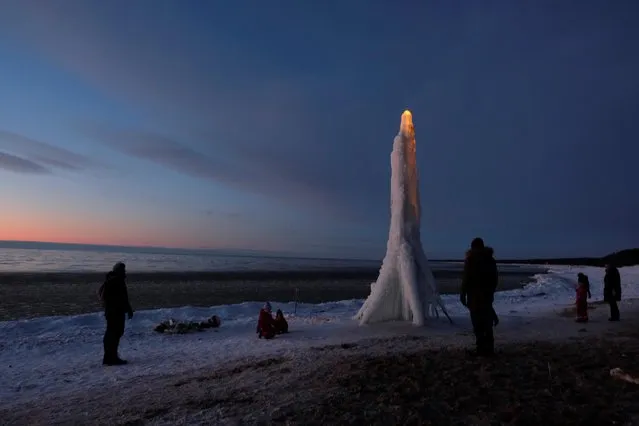 People gather next to an ice sculpture made by locals in the beach in Saulkrasti, Latvia on February 15, 2021. (Photo by Ints Kalnins/Reuters)