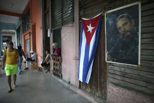 A Cuban flag and an image of Cuba's late President Fidel Castro hang on a wall as people head to Revolution Square for a massive tribute to Castro in Havana, Cuba, November 29, 2016. (Photo by Alexandre Meneghini/Reuters)