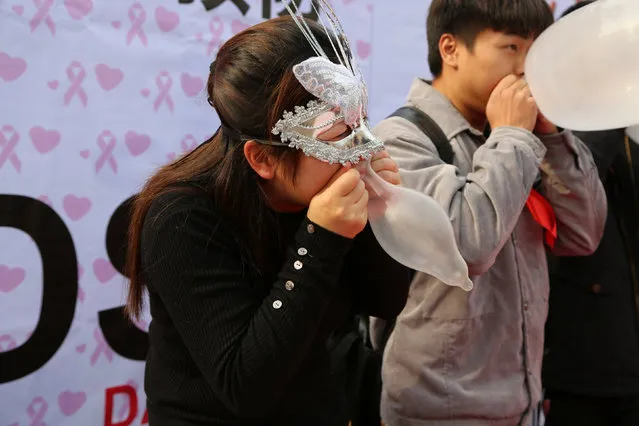 People blow to inflate condoms as they participate in a promotional event for AIDS prevention in Chongqing Municipality ahead of the World AIDS Day, China, November 30, 2016. (Photo by Reuters/Stringer)