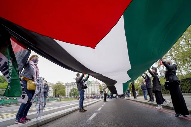 People hold a Palestinian flag as they march in solidarity with the Palestinian people amid the ongoing conflict with Israel, during a demonstration in London, Saturday, May 15, 2021. (Photo by Alberto Pezzali/AP Photo)