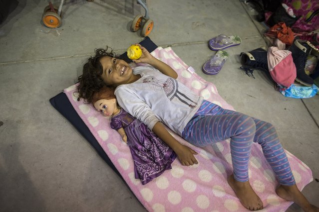 A girl relaxes next to her doll inside a temporary shelter set up for a splinter group of a migrant caravan hoping to reach the U.S. border, in Cordoba, Veracruz state, Mexico, Sunday, November 4, 2018. Thousands of wary Central American migrants resumed their push toward the United States on Sunday, entering a treacherous part of the caravan’s journey on a trek through one of Mexico’s deadliest states, along what some called the “route of death” toward the town of Cordoba, Veracruz. (Photo by Rodrigo Abd/AP Photo)