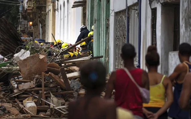 People watch firefighters clear debris from a building that partially collapsed in search for survivors in Havana, Cuba, Wednesday, October 4, 2023. (Photo by Ramon Espinosa/AP Photo)