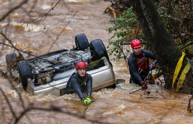 Firefighters Josh Crawford (L) and Andrew Dalton (R) with the Dekalb County Fire Rescue department's swift water rescue team work to recover a car which drove into the rain-swollen Fowler Creek at the height of a heavy morning storm in Decatur, Georgia, USA, 03 February 2016. The female driver was thrown from the vehicle during the accident, but survived and was taken to an area hospital, according to Captain Eric Jackson. (Photo by Erik S. Lesser/EPA)