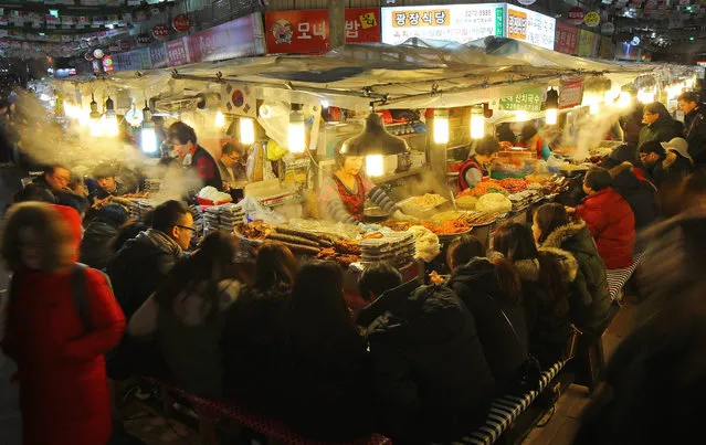 A picture taken with a slow shutter speed made available on 29 December 2016 shows steam from cooking pots filling the air at the food stalls of the Kwangjang Market in downtown Seoul, South Korea, 28 December 2016, as locals seek comfort from the wintry weather in the evening. Snow began falling across the country late in the day. (Photo by EPA/Yonhap)