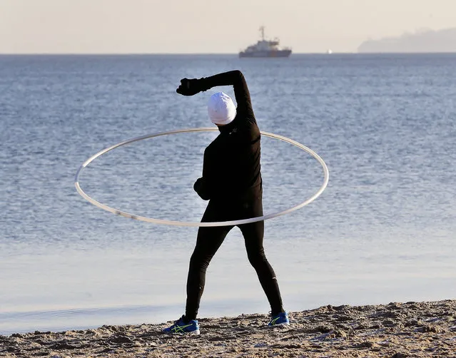 An old man exercises with a huge ring at he beach of the Baltic Sea on Timmendorfer Strand, Germany, Friday, December 30, 2016. (Photo by Michael Probst/AP Photo)