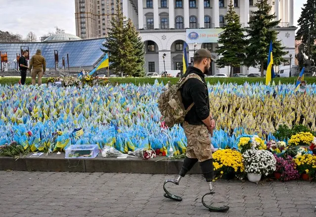 A serviceman, wearing prosthetic legs, walks past the Ukrainian flags symbolising the fallen soldiers on the Independence Square in Kyiv, on October 30, 2023, amid the Russian invasion of Ukraine. (Photo by Sergei Supinsky/AFP Photo)