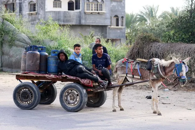 Children use a donkey-pulled cart to transport empty gas canisters to be filled with cooking gas from a tank that entered the Palestinian enclave via the Rafah crossing with Egypt, in Rafah in the southern Gaza Strip on November 25, 2023. Trucks carrying aid, including fuel, food and medicine, began moving into Gaza through the Rafah crossing from Egypt shortly after a truce began at 7:00 am (0500 GMT) on November 24, the biggest humanitarian convoy to enter the besieged territory since the war started on October 7 between Israel and the Palestinian Hamas movement. (Photo by Said Khatib/AFP Photo)