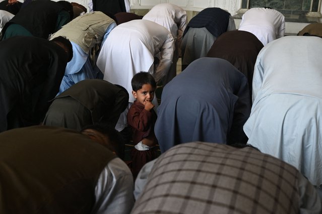 An child watches as Afghan devotees offer Eid al-Adha prayers inside a mosque in Kabul on July 20, 2021. (Photo by Sajjad Hussain/AFP Photo)