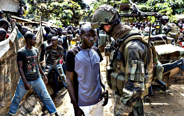 A man gives informations about ex-seleka rebels to a French soldier in Combattant neighborhood near Bangui's airport, on December 9, 2013. French troops on Monday began disarming fighters in the Central African Republic after a swell in sectarian violence that has claimed hundreds of lives and terrified inhabitants. (Photo by Fred Dufour/AFP Photo)