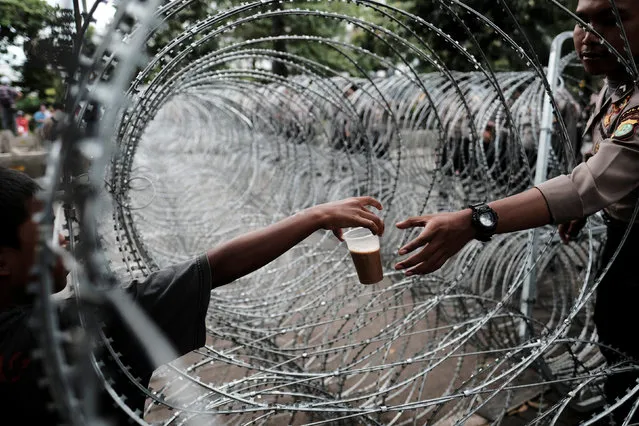 An Indonesian policeman buys a drink as he stands guard near the barbwire outside a court at the blasphemy trial of Jakarta's incumbent governor Basuki Tjahaja Purnama, also known as Ahok, in Jakarta, Indonesia January 10, 2017. (Photo by Reuters/Beawiharta)