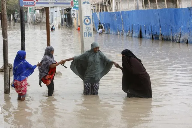Women walk through flood water after heavy rainfall, in Mogadishu Somalia, Monday, November 20, 2023. (Photo by Farah Abdi Warsameh/AP Photo)