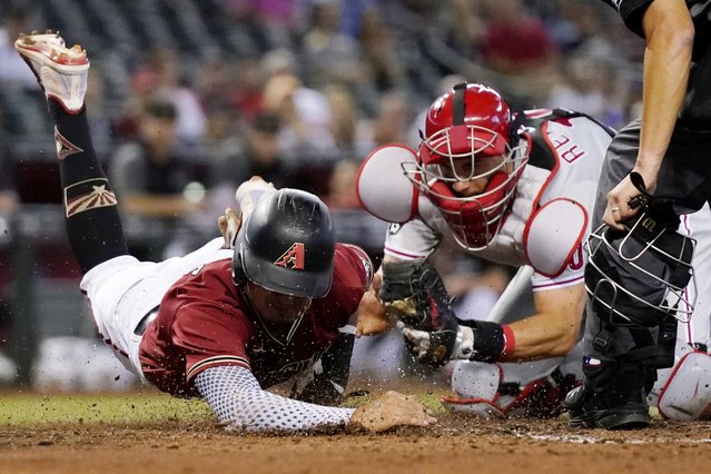 Philadelphia Phillies catcher J.T. Realmuto, right, tags out Arizona Diamondbacks' Josh Rojas, left, during the second inning of a baseball game, Wednesday, August 18, 2021, in Phoenix. (Photo by Ross D. Franklin/AP Photo)