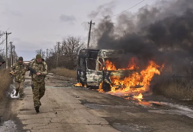 In this photo provided by the Ukrainian 10th Mountain Assault Brigade “Edelweiss”, Ukrainian soldiers pass by a volunteer bus burning after a Russian drone hit it near Bakhmut, Donetsk region, Ukraine, Thursday, November 23, 2023. (Photo by Shandyba Mykyta, Ukrainian 10th Mountain Assault Brigade “Edelweiss” via AP Photo)