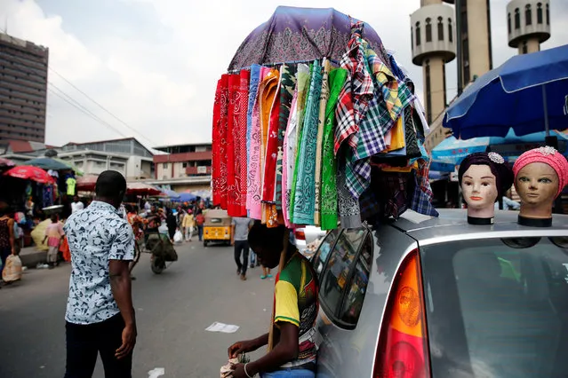A street vendor counts money near a vehicle parked along a road in the central business district, near Marina in Lagos, Nigeria December 13, 2016. (Photo by Akintunde Akinleye/Reuters)