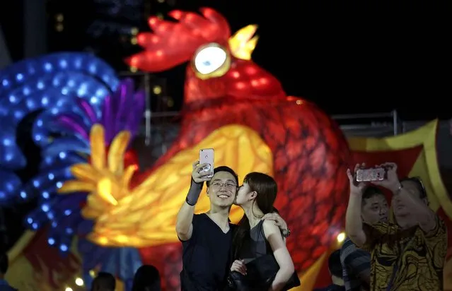 A couple takes a selfie in front of a giant illuminated sculpture of a rooster ahead of the Chinese lunar new year on Thursday, January 26, 2017 in Singapore. (Photo by Wong Maye-E/AP Photo)