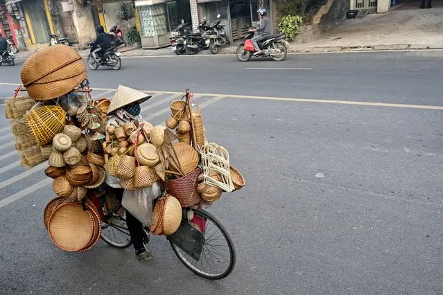 A woman rides a bicycle transporting bamboo and rattan household items for sale on a street in Hanoi on January 19, 2024. (Photo by Nhac Nguyen/AFP Photo)
