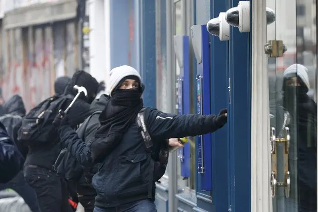 A demonstrator, with his face masked by a scarf, uses a hammer to attack a bank window during a protest by high school and university students against a French labour law proposal in Paris, France, March 9, 2016. (Photo by Charles Platiau/Reuters)