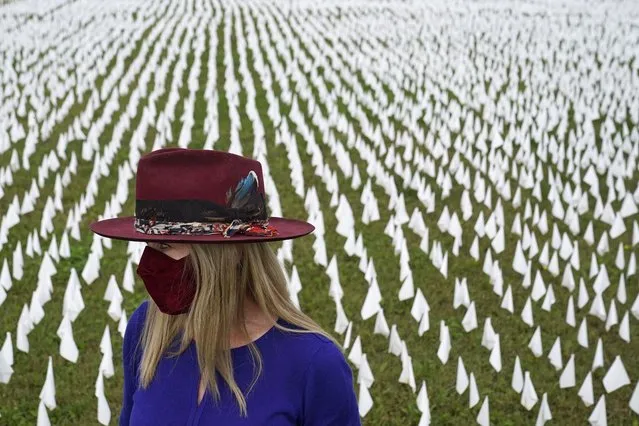 In this October 27, 2020, file photo, Artist Suzanne Brennan Firstenberg stands among thousands of white flags planted in remembrance of Americans who have died of COVID-19, near Robert F. Kennedy Memorial Stadium in Washington. Firstenberg's temporary art installation, called “In America, How Could This Happen”, will include an estimated 240,000 flags when completed. (Photo by Patrick Semansky/AP Photo/File)