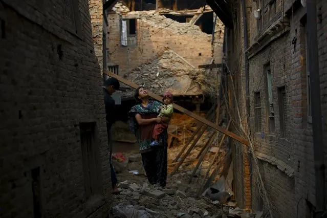 A woman carrying her child stands in an alley surrounded by damaged and collapsed houses following April 25 earthquake at Bhaktapur May 7, 2015. (Photo by Navesh Chitrakar/Reuters)