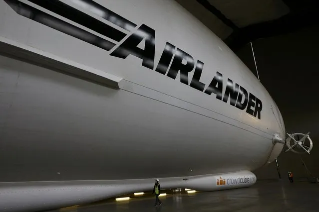 A worker walks alongside the Airlander 10 hybrid airship during its unveiling in Cardington, Britain March 21, 2016. (Photo by Darren Staples/Reuters)