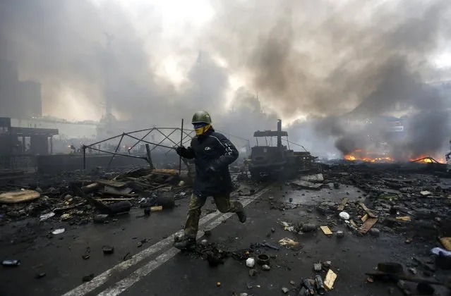 An anti-government protester runs trough the rubble after violence erupted in the Independence Square in Kiev February 20, 2014. (Photo by Yannis Behrakis/Reuters)