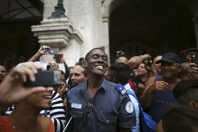 A security officer (C) cheers with the public as they wait for an eventual visit of U.S. President Barack Obama to downtown Havana, Cuba March 21, 2016. (Photo by Alexandre Meneghini/Reuters)