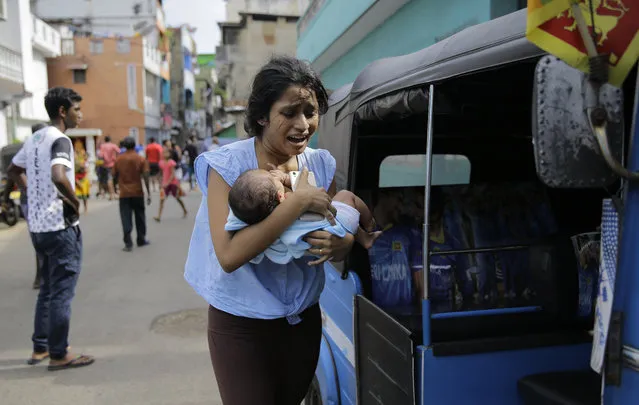 A Sri Lankan woman living near St. Anthony's shrine runs for safety with her infant after police found explosive devices in a parked vehicle in Colombo, Sri Lanka, Monday, April 22, 2019. Easter Sunday bombings that ripped through churches and luxury hotels killed more than 200 people. (Photo by Eranga Jayawardena/AP Photo)