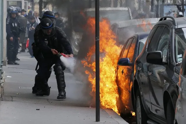 French police tries to extinguish a burning car during a demonstration by French high school and university students against the labour reform bill proposal in Paris, France, March 24, 2016 as part of a nationwide labor reform protest. (Photo by Gonzalo Fuentes/Reuters)
