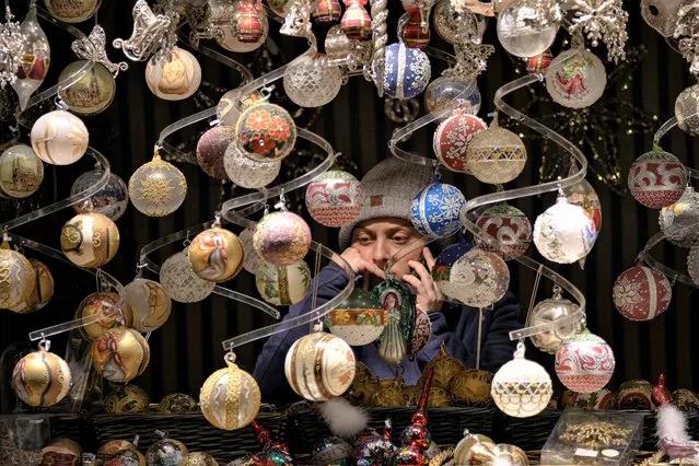 A vendor speaks on the phone at a Christmas market in Vienna, Austria, Saturday, November 20, 2021. The Austrian government announced a nationwide lockdown that will start Monday and comes as average daily deaths have tripled in recent weeks and hospitals in heavily hit states have warned that intensive care units are reaching capacity. (Photo by Vadim Ghirda/AP Photo)