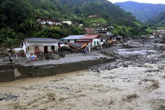 Residents stand in front of their damaged houses, after a landslide sent mud and water crashing onto homes close to the municipality of Salgar in Antioquia department, Colombia May 19, 2015. (Photo by Jose Miguel Gomez/Reuters)