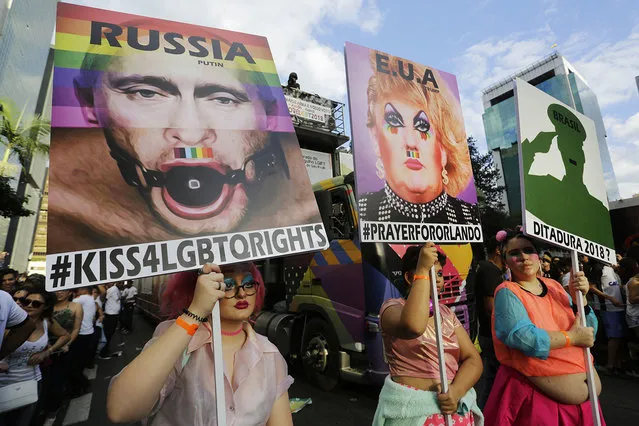 Revelers holds posters depicting United States President Donald Trump, and Russian President Vladimir Putin, left, as they march during the annual Gay Pride Parade in Sao Paulo, Brazil, June 18, 2017. (Photo by Nelson Antoine/AP Photo)