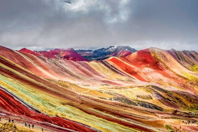 An array of colours dwarf visitors to the Rainbow Mountains in the Andes Cordillera in Peru in January 2023, which owes its colours to the minerals contained in the soil. The sulfur offers the yellow colour, iron oxide gives the red and copper sulfate is green. In total, it is made up of 14 different minerals. It was probably caused by weather and volcanic activity. (Photo by Guillaume Astruc/Naturagency/Solent News & Photo Agenc)