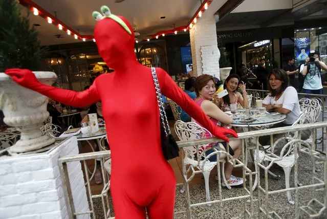 Diners look at a participant wearing Zentai costume, or skin-tight bodysuit from head to toe, during a march down the shopping district of Orchard Road as part of the Zentai Art Festival in Singapore May 23, 2015. (Photo by Edgar Su/Reuters)