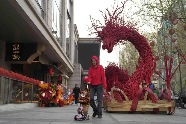 A woman and child past by a dragon sculpture outside a newly opened restaurant in Beijing, Tuesday, April 9, 2024. (Photo by Ng Han Guan/AP Photo)