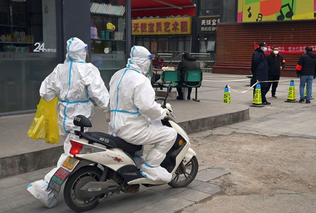 Delivery riders escort medical staff to a nucleic acid sampling site in Xi'an, northwest China's Shaanxi Province, December 30, 2021. After the outbreak of COVID-19 in Xi'an, many delivery riders volunteer to deliver daily necessities and register information for nucleic acid test. (Photo by Li Yibo/Xinhua/Alamy Live News)
