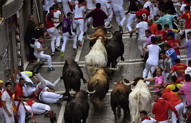 Revellers run next to fighting bulls during the running of the bulls at the San Fermin Festival, in Pamplona, northern Spain, Saturday, July, 13, 2019. Revellers from around the world flock to Pamplona every year to take part in the eight days of the running of the bulls. (Photo by Alvaro Barrientos/AP Photo)