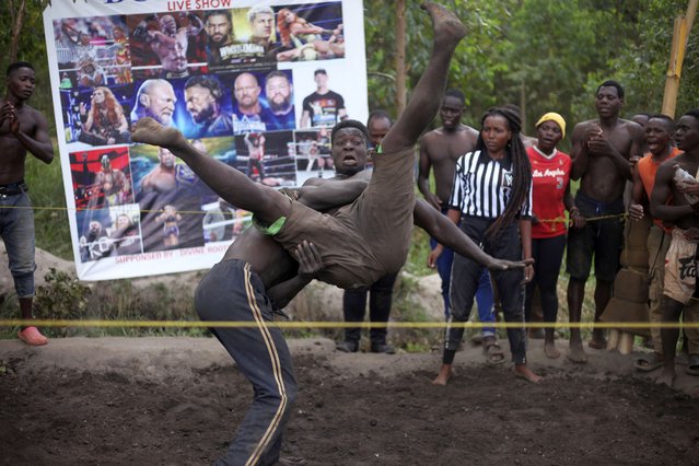 Amateur wrestlers tangle in what is known as Soft Ground Wrestling, in Kampala, Uganda March 20, 2024. The open-air training sessions, complete with an announcer and a referee, imitate the pro-wrestling contests the youth watch on television. (Photo by Patrick Onen/AP Photo)