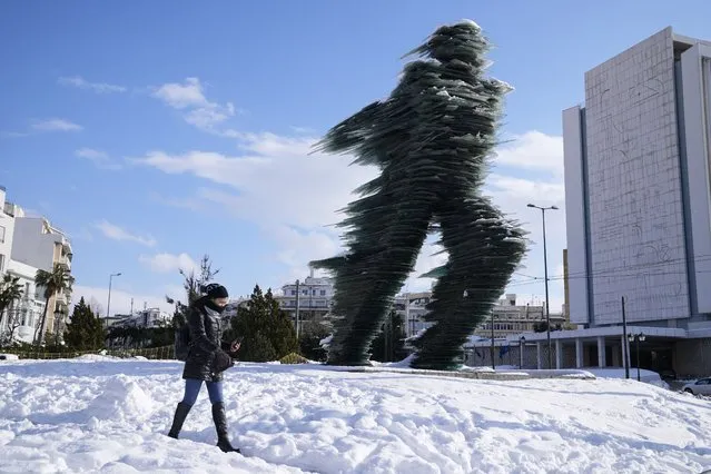 A woman walks past a the Runner, sculptured by Kostas Varotsos, after a snowstorm, in Athens, on Tuesday, January 25, 2022. A snowstorm of rare severity disrupted road and air traffic Monday in the Greek capital of Athens and neighboring Turkey's largest city of Istanbul, while most of Greece, including – unusually – several Aegean islands, and much of Turkey were blanketed by snow. (Photo by Thanassis Stavrakis/AP Photo)