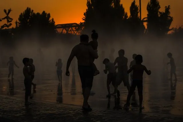 Children cool down in a fountain beside Manzanares river in Madrid,  Spain, Saturday, June 27, 2015. (Photo by Andres Kudacki/AP Photo)