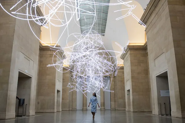 A gallery assistant poses for photographers during a photocall to promote Welsh artist's Cerith Wyn Evans new light installation entitled “Forms in Space... by Light (in Time)”, made up of nearly 2km of neon lights, at Tate Britain in London on March 27, 2017. The exhibition is set to run from March 28, to August 20, 2017. (Photo by Justin Tallis/AFP Photo)