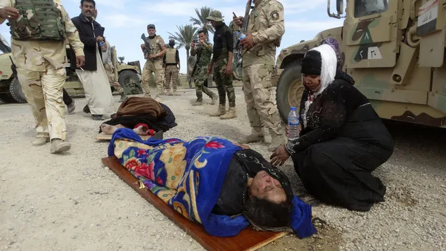 An injured woman comforts another as they wait for treatment after clashes between Iraqi forces and Islamic State group extremists in a village outside Ramadi, in this March 9, 2016 file photo. Months after Iraqi troops wrested control of Ramadi from the militants, most of the city's population of 1 million remains displaced, unable to return because of continued fighting in surrounding areas and massive destruction. (Photo by Osama Sami/AP Photo)