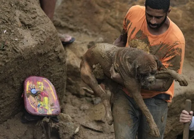 A man rescues a dog from a residential area destroyed by mudslides in Petropolis, Brazil, Wednesday, February 16, 2022. Extremely heavy rains set off mudslides and floods in a mountainous region of Rio de Janeiro state, killing multiple people, authorities reported. (Photo by Silvia Izquierdo/AP Photo)